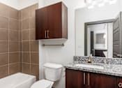 Thumbnail 3 of 13 - SevenTwelve Lofts Downtown UNT Denton Apartments A bathroom with a toilet, sink, and mirror.