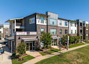 Thumbnail 12 of 13 - SevenTwelve Lofts Downtown UNT Denton Apartments A building with the sign "LOFTS NOW AVAILABLE" in front of it.