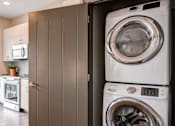 Thumbnail 18 of 27 - A white washing machine is in a cabinet in a modern kitchen. at 985 High Apartments, Ohio, 43201