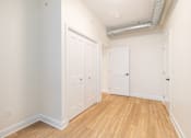 Thumbnail 10 of 20 - a bedroom with white walls and wood flooring and two closets