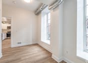 Thumbnail 6 of 20 - a living room with white walls and wood floors and a large window