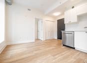 Thumbnail 4 of 20 - a renovated kitchen and living room with white cabinets and a stainless steel refrigerator