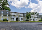 Thumbnail 24 of 25 - Apartment building with a parking lot in front.