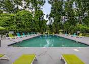 Thumbnail 25 of 25 - A large outdoor swimming pool surrounded by trees and lounge chairs.