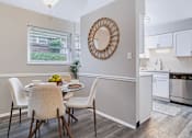 Thumbnail 7 of 38 - A dining room with a round mirror and a table set for two.