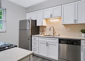 Thumbnail 10 of 38 - A kitchen with white cabinets and a black refrigerator.