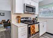 Thumbnail 9 of 38 - A kitchen with a stove top oven and a microwave above it.