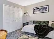Thumbnail 16 of 38 - A bedroom with a bed, a chair, and a painting on the wall.