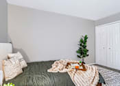 Thumbnail 15 of 38 - A cozy bedroom with a bed covered in a green comforter and a tray with a book and a plant on it.