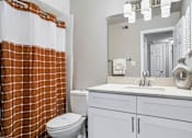 Thumbnail 18 of 38 - A bathroom with a toilet, sink, and shower curtain.