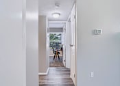 Thumbnail 11 of 38 - A hallway with a door on the right and a window with a view of trees outside.