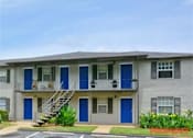 Thumbnail 4 of 5 - A grey apartment building with blue doors and windows.