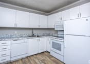 Thumbnail 2 of 5 - A kitchen with white cabinets and appliances.