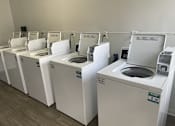 Thumbnail 3 of 5 - A row of washing machines are lined up in a laundromat.
