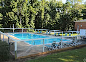 Thumbnail 1 of 5 - A pool surrounded by trees and chairs.