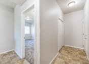 Thumbnail 7 of 23 - A white room with a doorway leading to another room.
