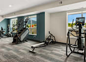 Thumbnail 29 of 98 - A gym with treadmills, elliptical machines, and a stair climber at The Beaumont Apartments, Montana, 59715