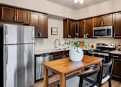 Thumbnail 1 of 27 - A kitchen with a wooden table and chairs, a refrigerator, a microwave, and a stove at Brooklyn West Apartments, Missoula, MT, 59808