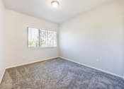 Thumbnail 8 of 23 - A room with a carpeted floor and a window with blinds.