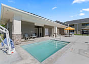 Thumbnail 28 of 40 - A pool area with a diving board and a building in the background.