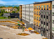 Thumbnail 77 of 98 - A modern apartment complex with a parking lot in front at The Beaumont Apartments, Montana, 59715