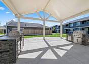Thumbnail 30 of 40 - A patio with a white canopy and a stone wall.