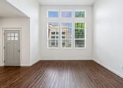 Thumbnail 29 of 61 - A room with a wooden floor and a large window with a view of a building outside. at Verraso Village Apartments, Meridian, Idaho