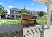 Thumbnail 31 of 40 - A modern outdoor kitchen with a grill and a stone countertop.