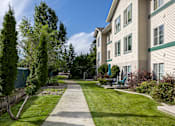Thumbnail 19 of 31 - a walkway between two apartment buildings with grass and trees
