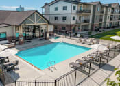 Thumbnail 3 of 46 - A large swimming pool surrounded by a black fence and lounge chairs.
