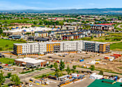 Thumbnail 78 of 98 - A large building complex with a parking lot in front at The Beaumont Apartments, MT 59715