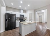 Thumbnail 32 of 61 - A kitchen with a black refrigerator, microwave, and stove top oven. at Verraso Village Apartments, Idaho