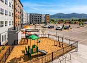 Thumbnail 59 of 98 - A playground with a grey slide and play area at The Beaumont Apartments, Bozeman