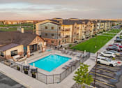 Thumbnail 1 of 46 - A large apartment complex with a pool in the foreground.