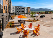 Thumbnail 71 of 98 - A patio with orange chairs and a table with a white tablecloth at The Beaumont Apartments, Montana, 59715