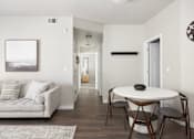 Thumbnail 16 of 26 - a small table and chairs in a living room with a couch and a hallway in the background at The Alloy at Geneva, Vineyard, UT, 84058
