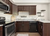 Thumbnail 18 of 26 - a kitchen with dark cabinets and granite counter tops at The Alloy at Geneva, Vineyard, Utah