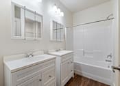 Thumbnail 39 of 61 - A white bathroom with a double sink vanity and a walk-in shower. at Verraso Village Apartments, Meridian, ID