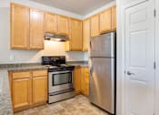 Thumbnail 4 of 23 - A kitchen with wooden cabinets and a stainless steel refrigerator.