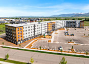 Thumbnail 86 of 98 - A large multi-story building with a parking lot in front at The Beaumont Apartments, Bozeman