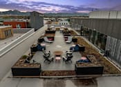 Thumbnail 23 of 23 - A rooftop patio with a table and chairs surrounded by planters at Cannery Flats, Bozeman, Montana