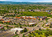 Thumbnail 85 of 98 - A large parking lot is surrounded by buildings and a road at The Beaumont Apartments, Montana