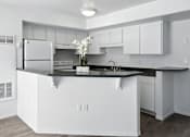 Thumbnail 33 of 43 - A modern kitchen with white cabinets and a black countertop. at Oakstone Apartments, Clearfield, 84015
