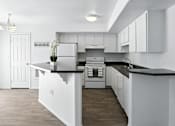 Thumbnail 31 of 43 - A kitchen with white cabinets and a black countertop. at Oakstone Apartments, Clearfield, 84015