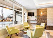 Thumbnail 25 of 35 - a living room with yellow chairs and a fireplace at Corso Apartments, Missoula, MT