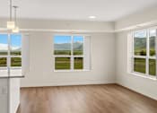 Thumbnail 7 of 98 - Spacious room with plank flooring, a small view of the kitchen island, and three large windows with a view of the mountains at The Beaumont Apartments, Montana, 59715