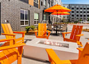 Thumbnail 72 of 98 - A patio with orange chairs and a fire pit at The Beaumont Apartments, Bozeman, MT