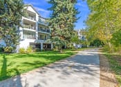 Thumbnail 40 of 48 - a sidewalk in front of an apartment building with trees and grass at River Walk Apartments, Boise, ID