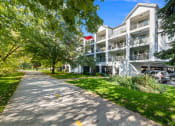 Thumbnail 4 of 48 - a sidewalk in front of a white apartment building with trees and grass at River Walk Apartments, Boise, 83702