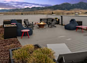 Thumbnail 15 of 23 - A patio with a table, chairs, and a fire pit with mountains in the background at Cannery Flats, Bozeman, Montana